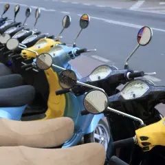 Línea de motos y scooters de colores aparcadas en la calle. Para saber si una moto está libre de cargas, revisa su documentación.