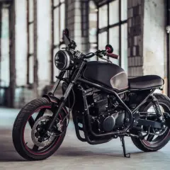 Elegante moto customizada, negra y con detalles rojos, lista para la aventura. Una moto sin papeles que inspira libertad y rebeldía.