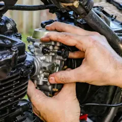 Manos ajustando el ahogador de moto, pieza clave para el arranque en frío.