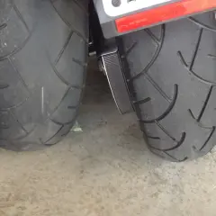 Dos ruedas de moto, una rueda moto gastada con dibujo casi liso y otra con más surcos, sobre suelo de hormigón.