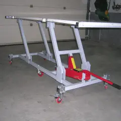 Elevador moto casero con gato hidráulico rojo, estructura metálica gris y ruedas. Ideal para reparaciones.