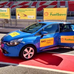 Coche azul en circuito con pegatinas Shell FuelSave, promocionando conducción eficiente.