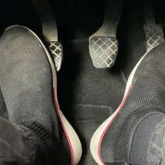 Pies con zapatillas negras listas para arrancar. Hay que pisar el embrague para arrancar el coche.