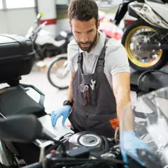 Mecánico revisa en laptop por qué la moto se para en marcha y no arranca.