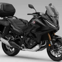 Moto automática Honda negra, lista para viajar con maletas laterales y top case.