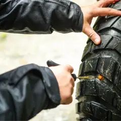 Manos arreglando pinchazo moto con kit de reparación.