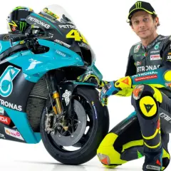 Valentino Rossi posa junto a su moto de competición, luciendo su icónico traje de carreras.