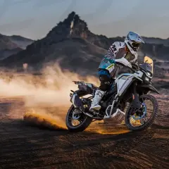 Motociclista en una CF Moto 450 MT, levantando polvo en un paisaje desértico. Conoce la cf moto 450 mt ficha técnica.