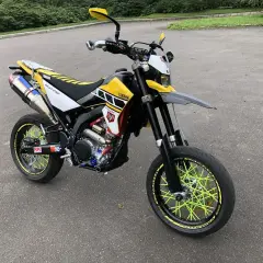 Yamaha WR 250 X personalizada con rines de radios amarillos brillantes y escape deportivo.
