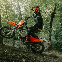 Motociclista en KTM salta en un sendero boscoso. ¡Las últimas ktm noticias sobre enduro!