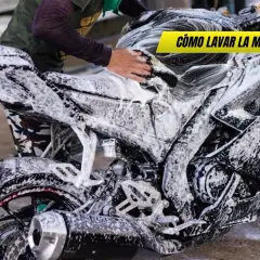 Persona lavando una moto deportiva con espuma. Se ve el motor, la rueda trasera y el tubo de escape. ¡Así se limpia la moto!