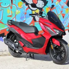 Scooter SYM Jet X 125 rojo brillante, con diseño deportivo, frente a un muro con grafitis coloridos. ¡Un estilo que inspira buenas opiniones!