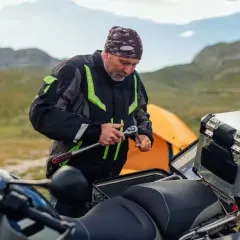 Motociclista repara su moto en la montaña, quizás para evitar que se ahoga la moto.