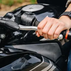 Mano sujetando el manillar de una moto negra, lista para arrancar. Aprender a no picar embrague es clave para una conducción suave.