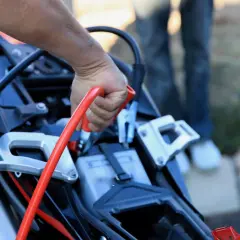 Mano conectando pinza roja para cargar bateria moto.