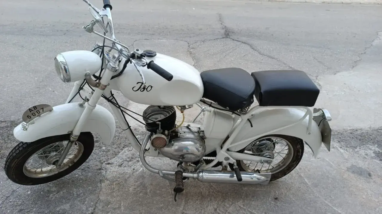 Ciclomotor histórico blanco, modelo Iso, con asiento doble y detalles cromados.