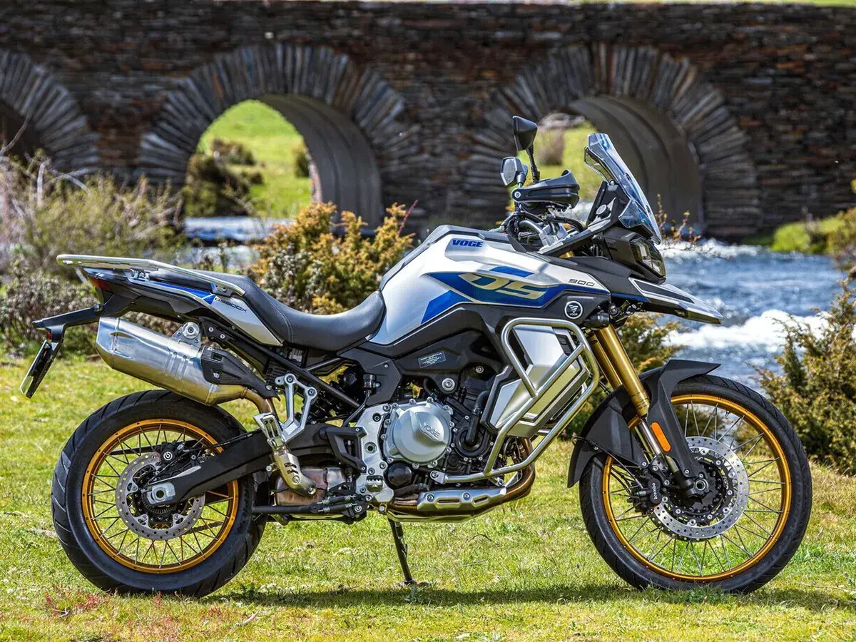 Moto Voge 500DS, una moto china con motor BMW, lista para la aventura junto a un puente de piedra.