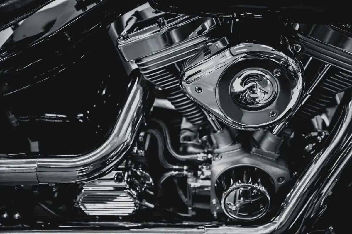 Detalle de un motor de motocicleta cromado, mostrando el sistema de alimentación y sus componentes.