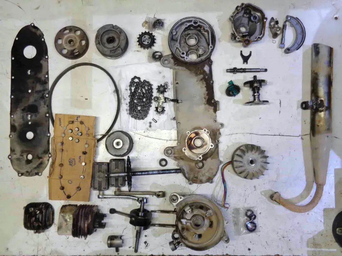 Despiece de una moto: carcasa, cadena, engranajes, cigüeñal, pistón, ventilador, escape y otras partes.