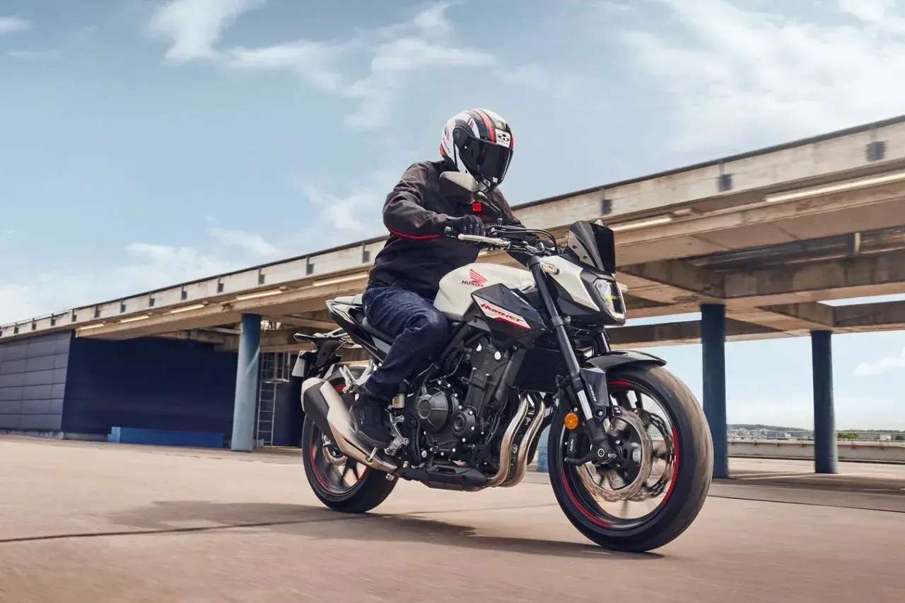 Hombre en moto Honda Hornet blanca y negra, con casco, acelerando. El motor de la moto ratea al acelerar, pero la experiencia es emocionante.