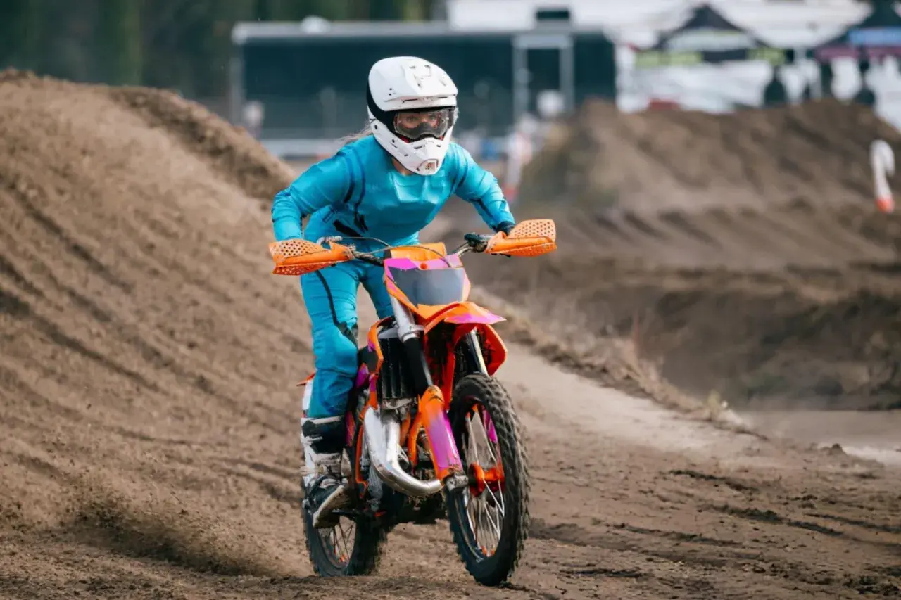 Piloto en moto 50cc azul y naranja compite en circuito de tierra. ¡Sorprende cuanto corre una 50cc!