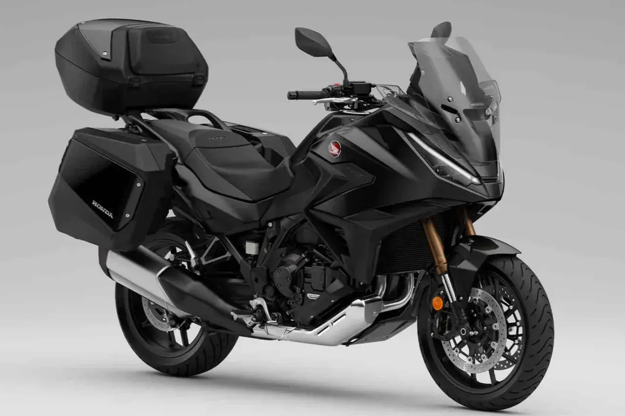 Moto automática Honda negra, lista para viajar con maletas laterales y top case.