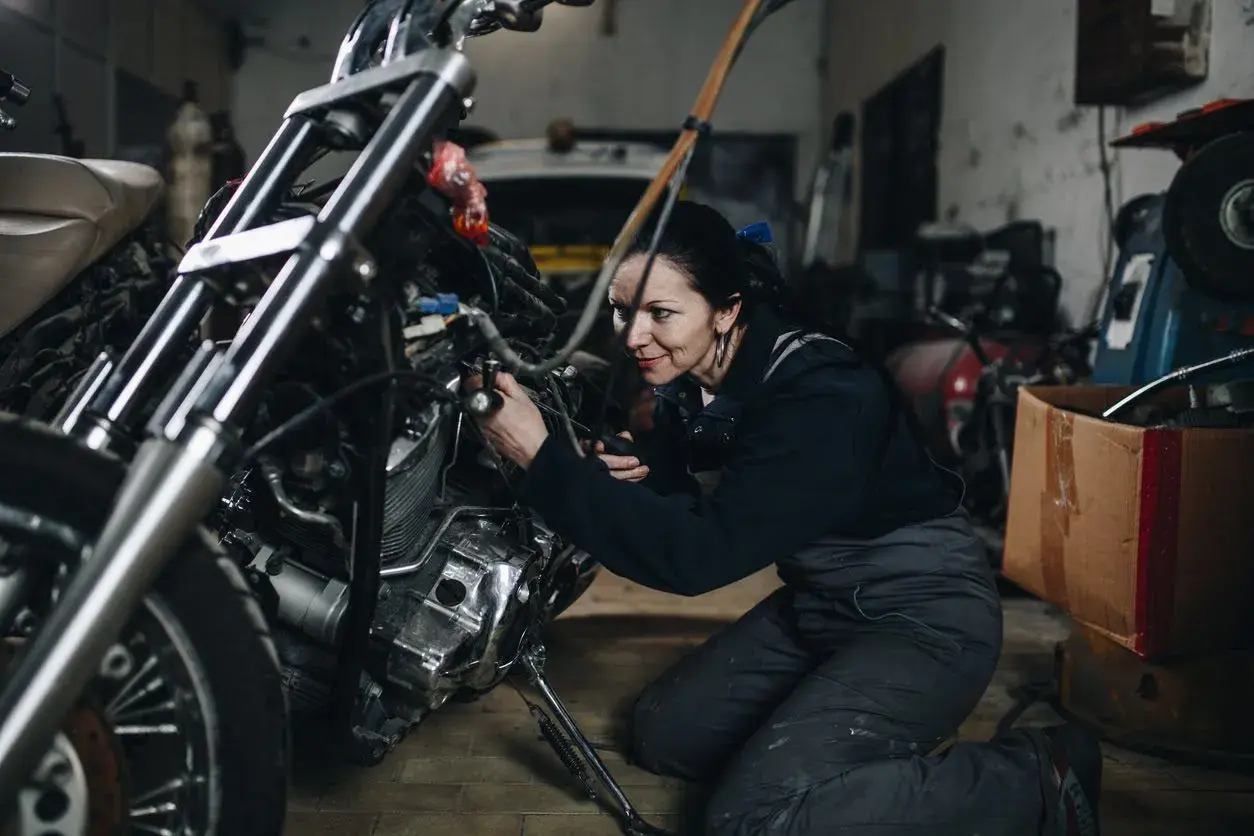 Mecánica arregla una moto ahogada en su taller.