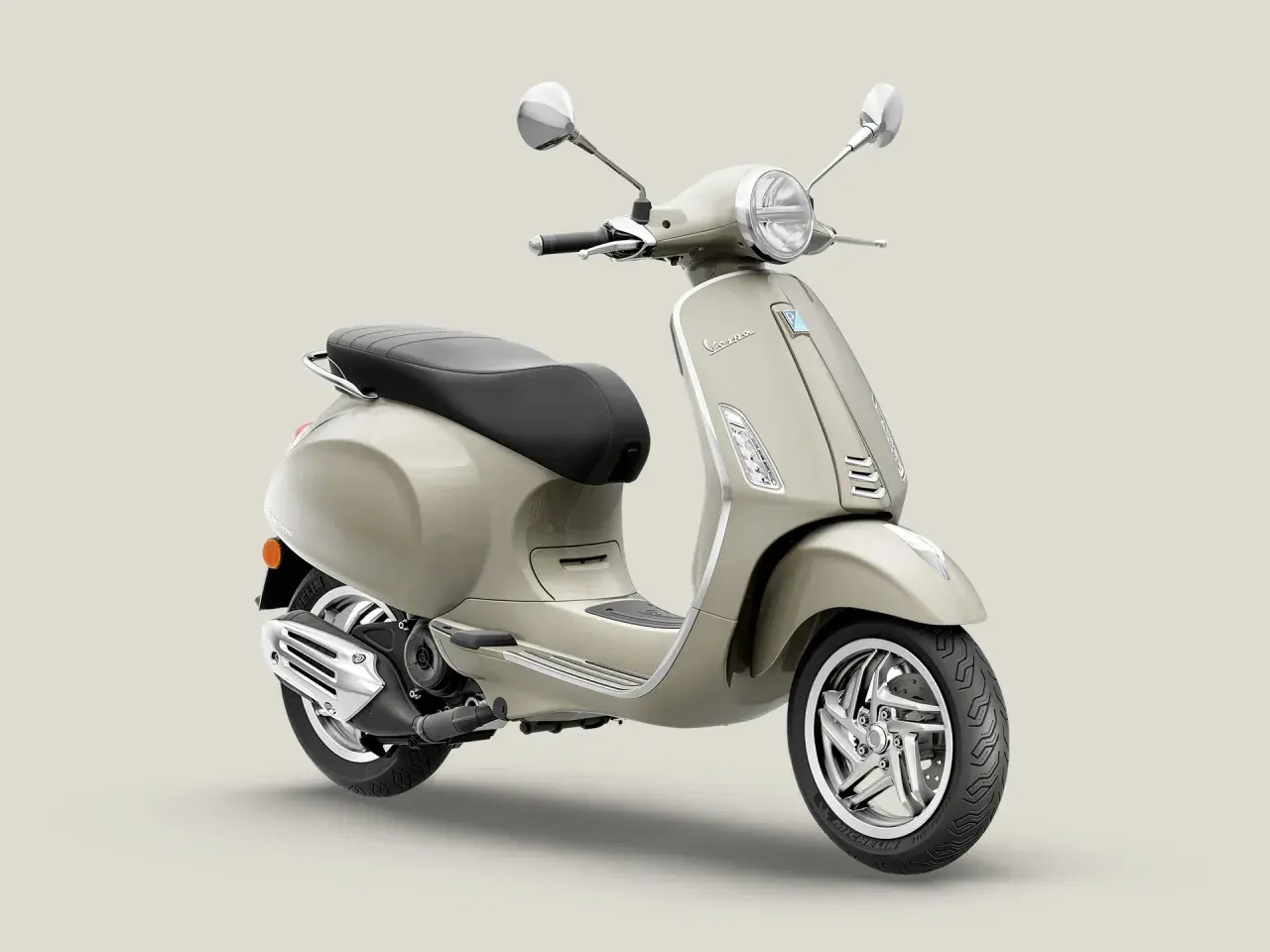 Vespa Primavera 50 color arena, con asiento negro y detalles cromados. Ideal para paseos urbanos.