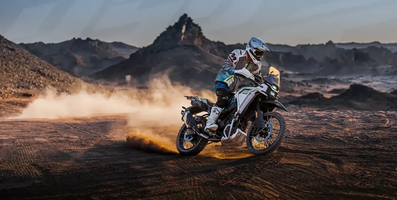 Motociclista en una CF Moto 450 MT, levantando polvo en un paisaje desértico. Conoce la cf moto 450 mt ficha técnica.