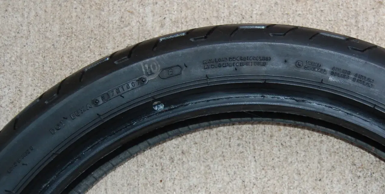 Detalle de la nomenclatura de llantas de motocicleta, mostrando información de carga, presión y composición.