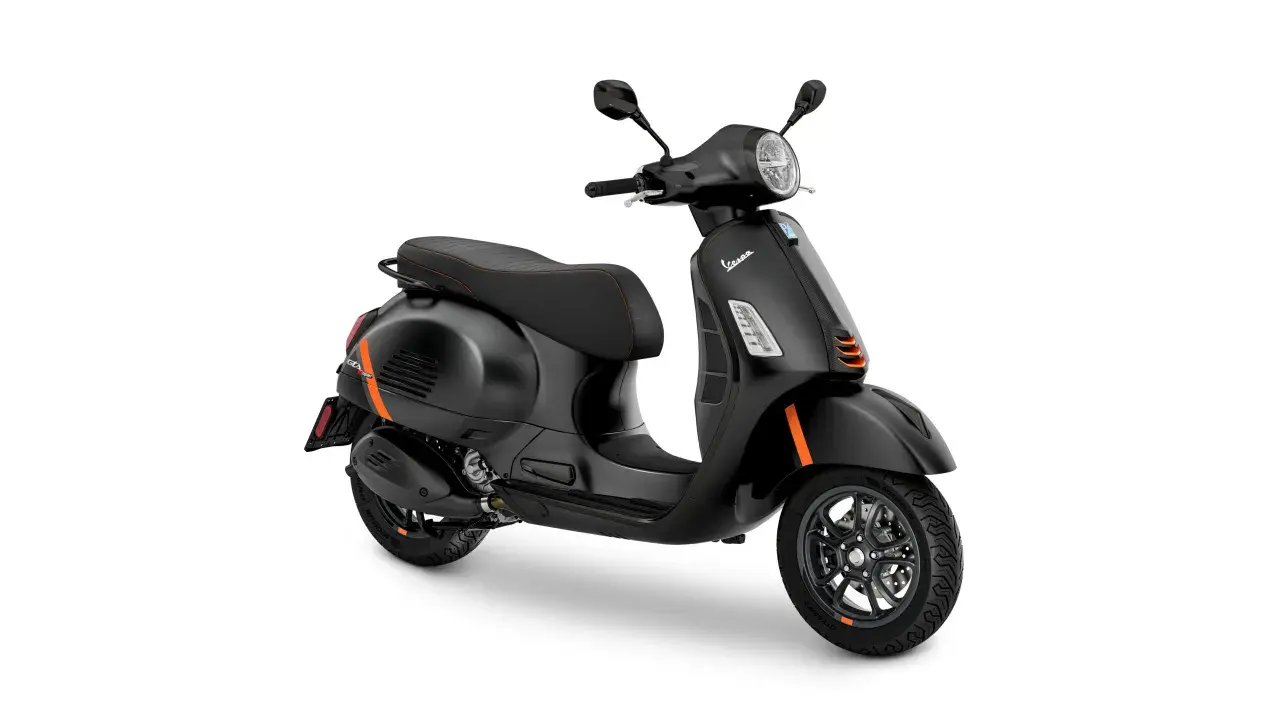 Vespa GTS 300 negra con detalles naranjas, asiento deportivo y llantas de aleación.