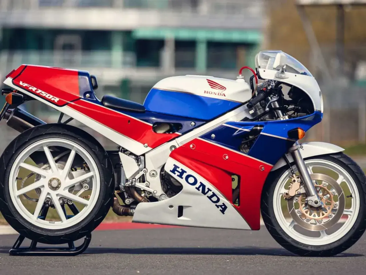 La icónica Honda RC30 VFR750R, con su distintivo tricolor rojo, blanco y azul, lista para la pista.
