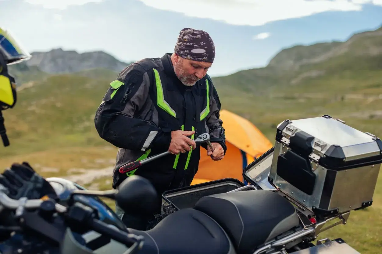 Motociclista repara su moto en la montaña, quizás para evitar que se ahoga la moto.