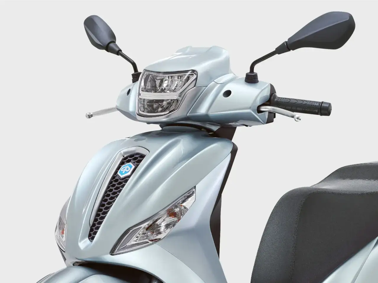 Detalle frontal de una Piaggio Medley 125 en un elegante color plateado. Se aprecian el faro, el logo y el asiento.