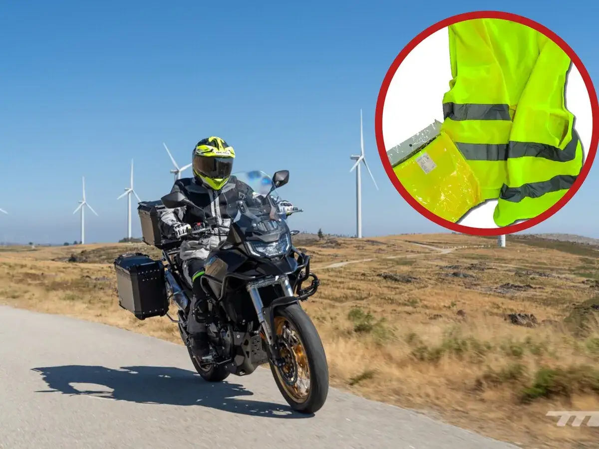 Motociclista en ruta con molinos de viento de fondo. Un chaleco reflectante, esencial y obligatorio en moto, se muestra en primer plano.