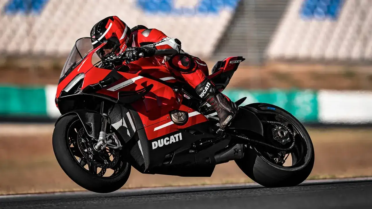 Piloto en moto Ducati roja en circuito. Es la ducati más cara, con detalles en fibra de carbono y equipamiento de alta gama.