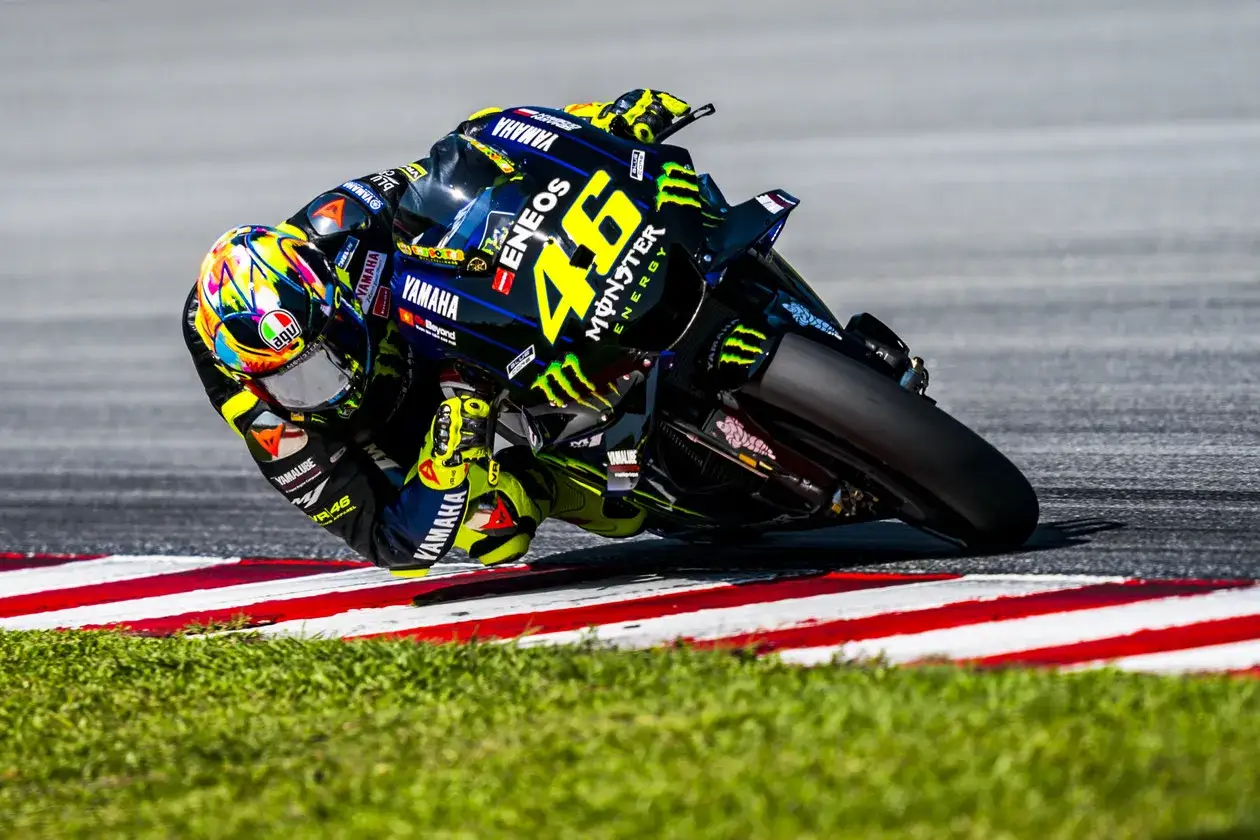 Piloto de la moto Valentino Rossi inclinado en una curva, con su icónico número 46 en la Yamaha.