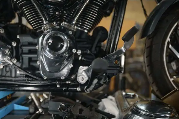 Detalle del motor de una motocicleta, mostrando el embrague y la palanca de cambios.